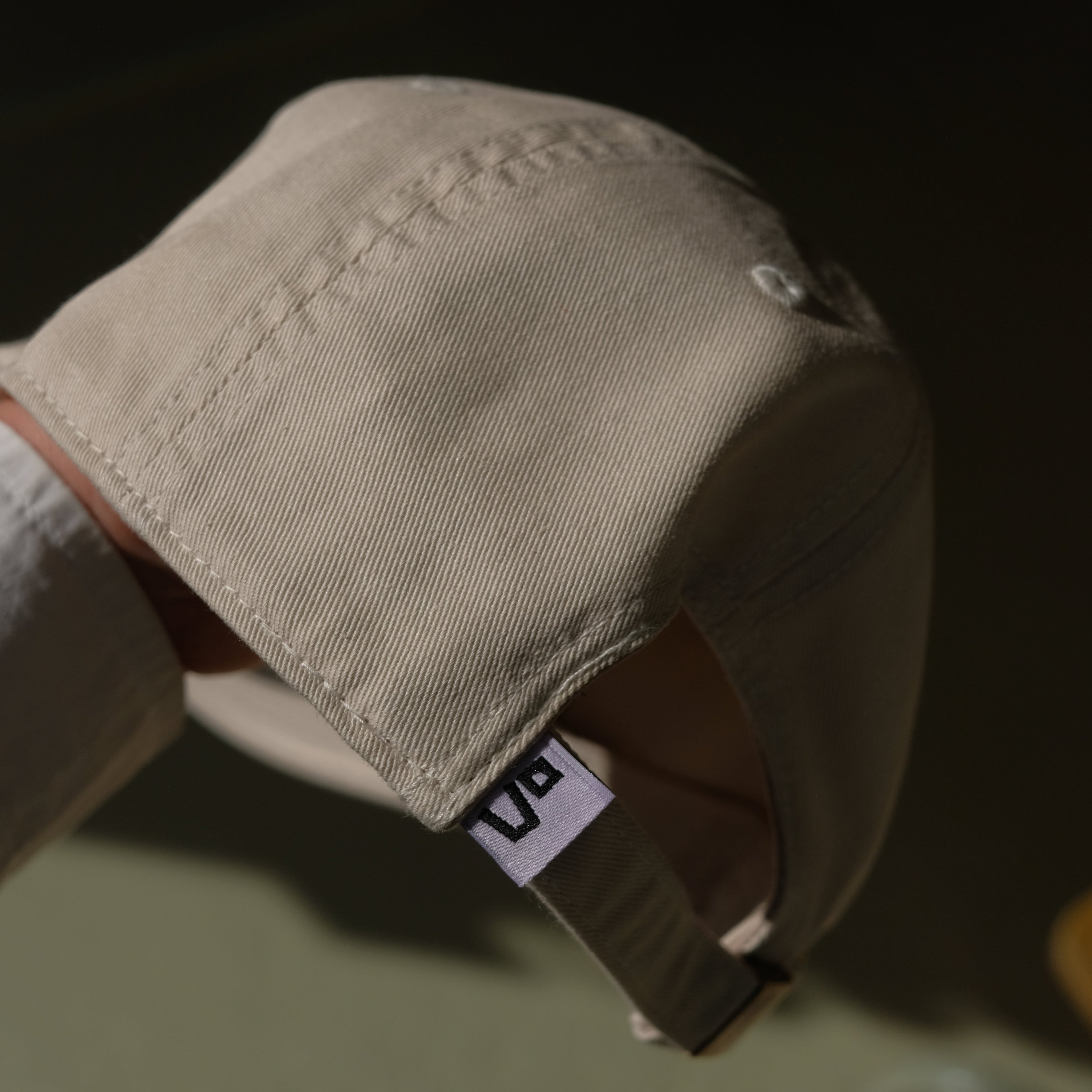 Beige cap with the vo logo on a blurred background