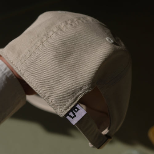 Beige cap with the vo logo on a blurred background